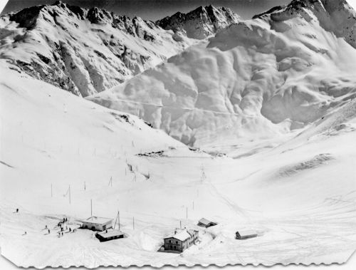 Postkarte der 1960er-Jahre, Service Aerien Perrochet, Blick über die Oberalp-Passhöhe nach Süden, Piz Cavradi (Privatarchiv skiliftfotos.ch). Auch sichtbar das Restaurant "Passhöhe" (heute "Alpsu"), das seinerzeit der Familie des Galeriebetreibers gehörte.
